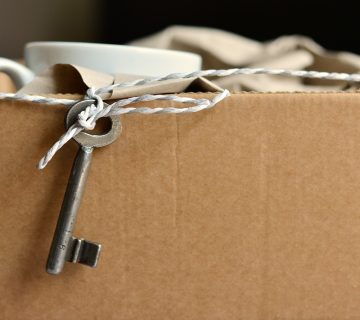 A vintage key tied to a string on a cardboard box.